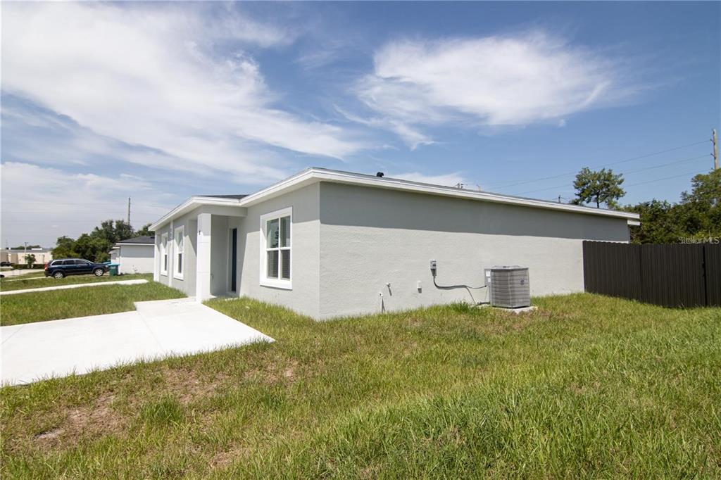 A side view of a single-story gray house with a concrete walkway and air conditioner — 2232 FERNWOOD STREET, DELTONA, FL