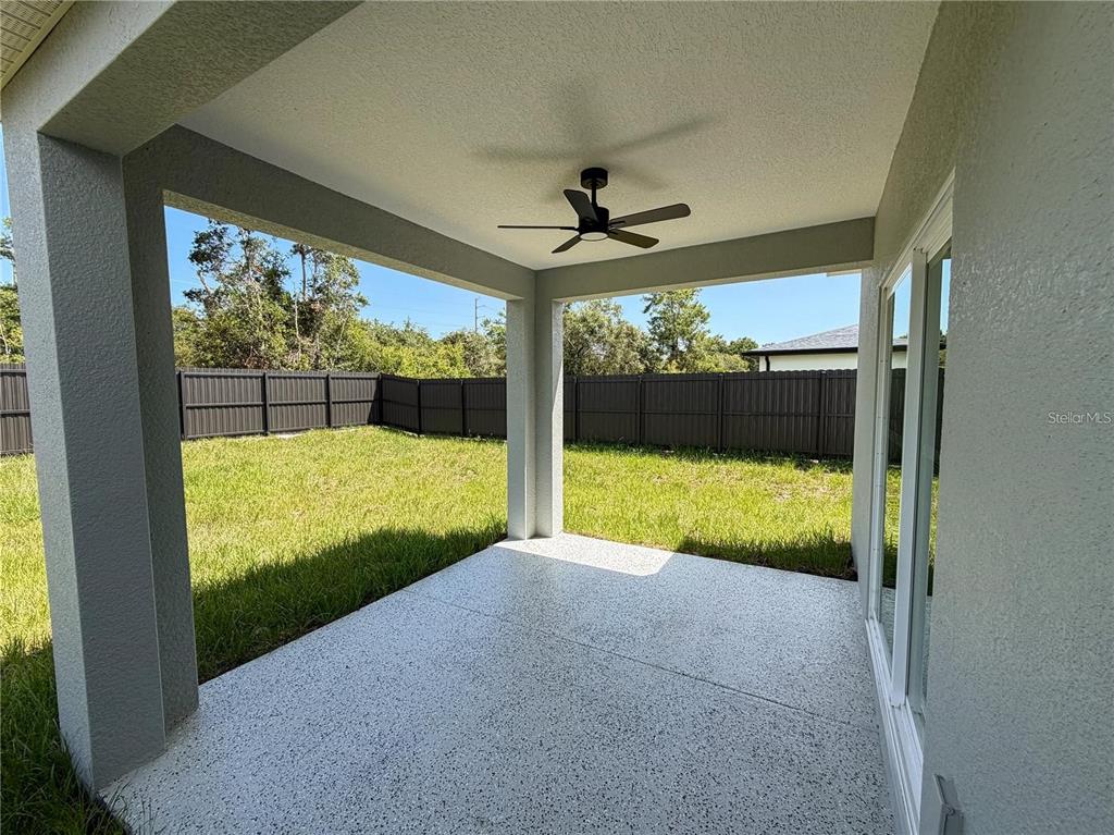 A covered concrete patio features a ceiling fan and overlooks a fenced backyard — 2232 FERNWOOD STREET, DELTONA, FL