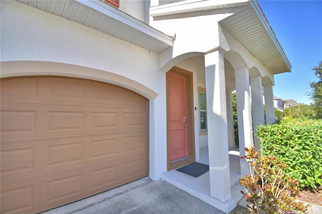 A tan garage door sits beside a covered entryway with a salmon-colored front door — 193 ABERDEEN STREET, DAVENPORT, FL