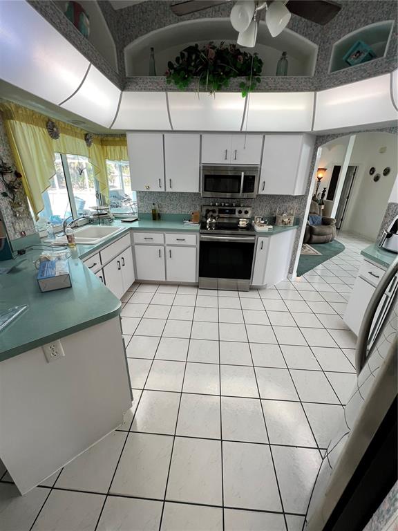 A kitchen features white cabinets, teal countertops, white tile flooring, and a stainless steel stove — 4009 ATWATER DRIVE, NORTH PORT, FL