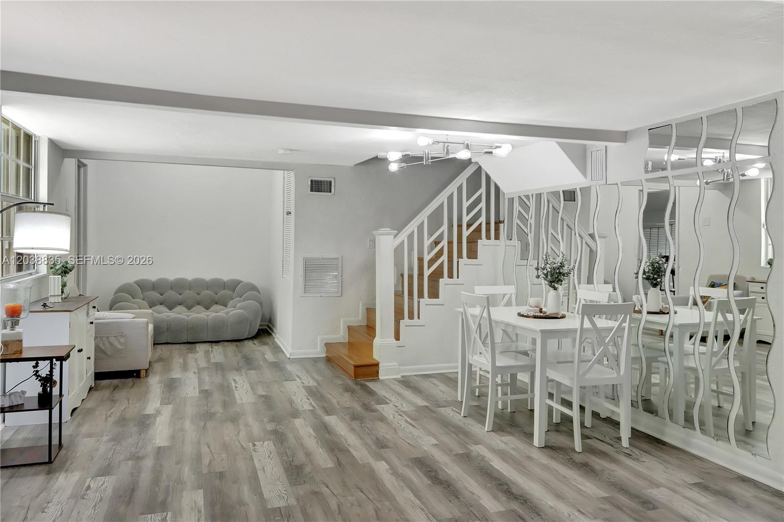 A dining area and living space feature wood-look flooring, a staircase, and mirrored walls — 3375 SW 29th Ter, Miami FL 33133, MIAMI, FL