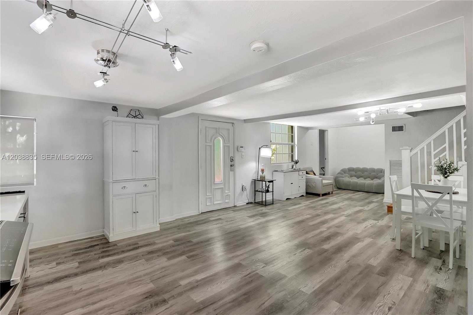 This open-concept living and dining area features light wood-look flooring and white cabinetry — 3375 SW 29th Ter, Miami FL 33133, MIAMI, FL