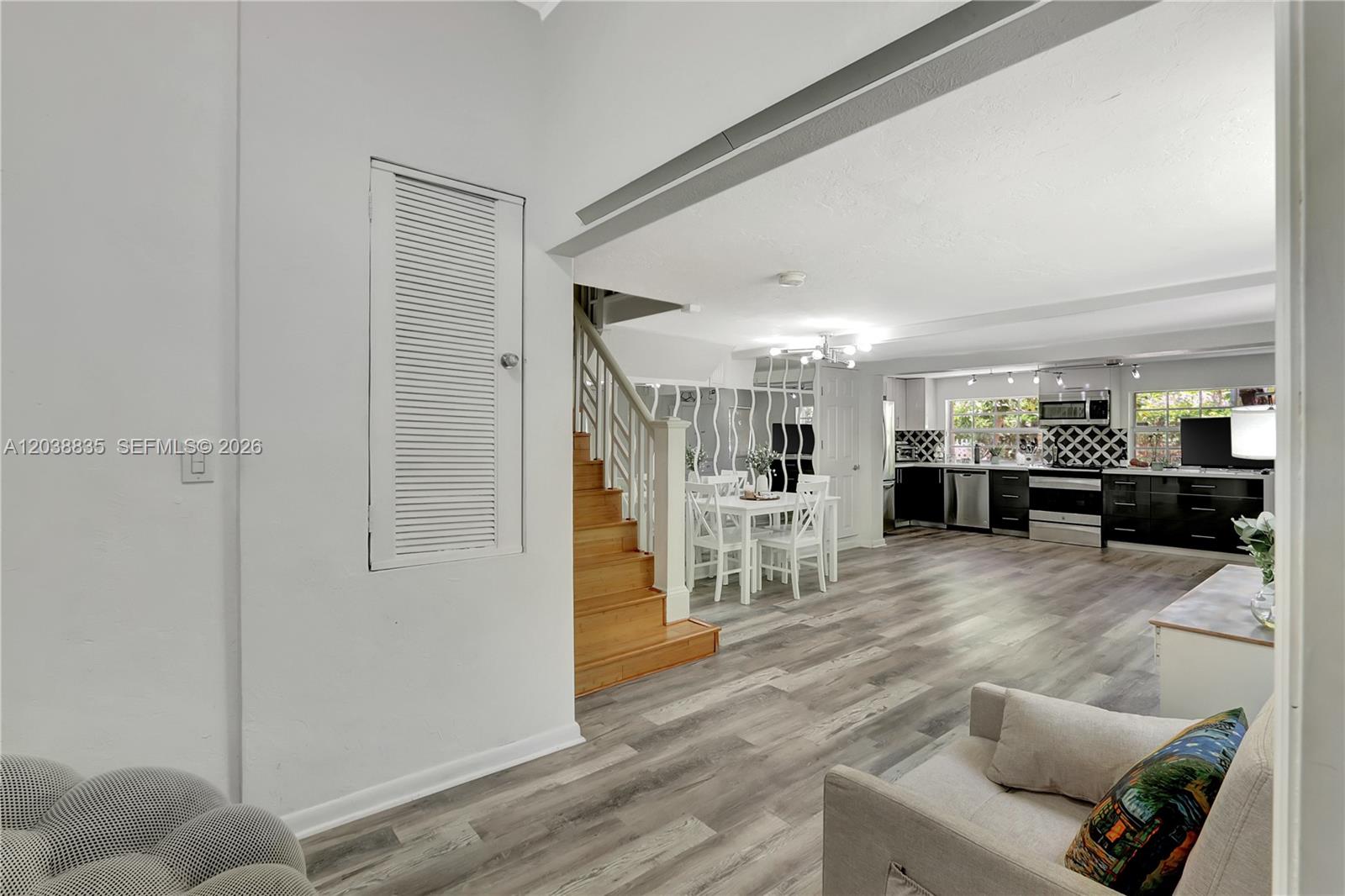 An open-concept living area features wood-look flooring, a staircase, and a modern kitchen — 3375 SW 29th Ter, Miami FL 33133, MIAMI, FL