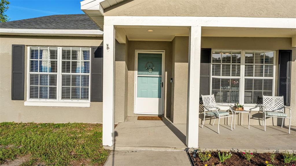 The exterior of a house features a covered porch, a light blue door, and two windows — 5563 STARLING LOOP, LAKELAND, FL