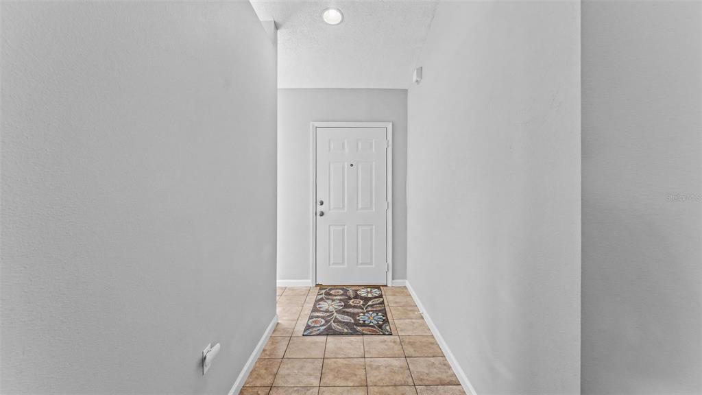 A tiled entryway features a white front door and light gray walls — 5563 STARLING LOOP, LAKELAND, FL
