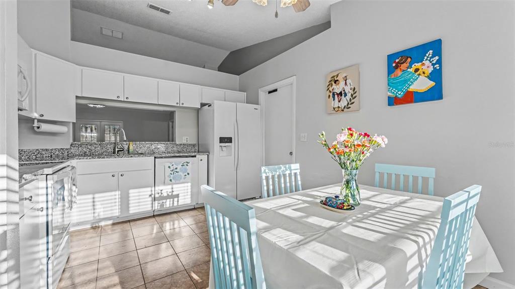 A kitchen with white cabinets, granite countertops, and a dining table with light blue chairs — 5563 STARLING LOOP, LAKELAND, FL