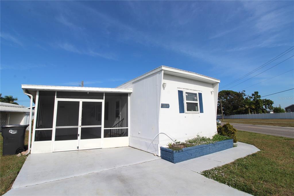 A white mobile home with a screened-in porch and a blue planter box in front — 503 51ST AVENUE W UNIT 503, BRADENTON, FL