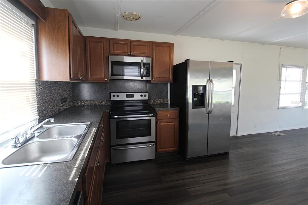 A kitchen features dark wood cabinets, stainless steel appliances, and dark countertops — 503 51ST AVENUE W UNIT 503, BRADENTON, FL