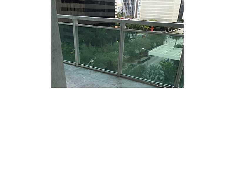 A balcony with a glass railing overlooks a city street and surrounding buildings — 951 Brickell Avenue # 701, Miami FL 33131, MIAMI, FL