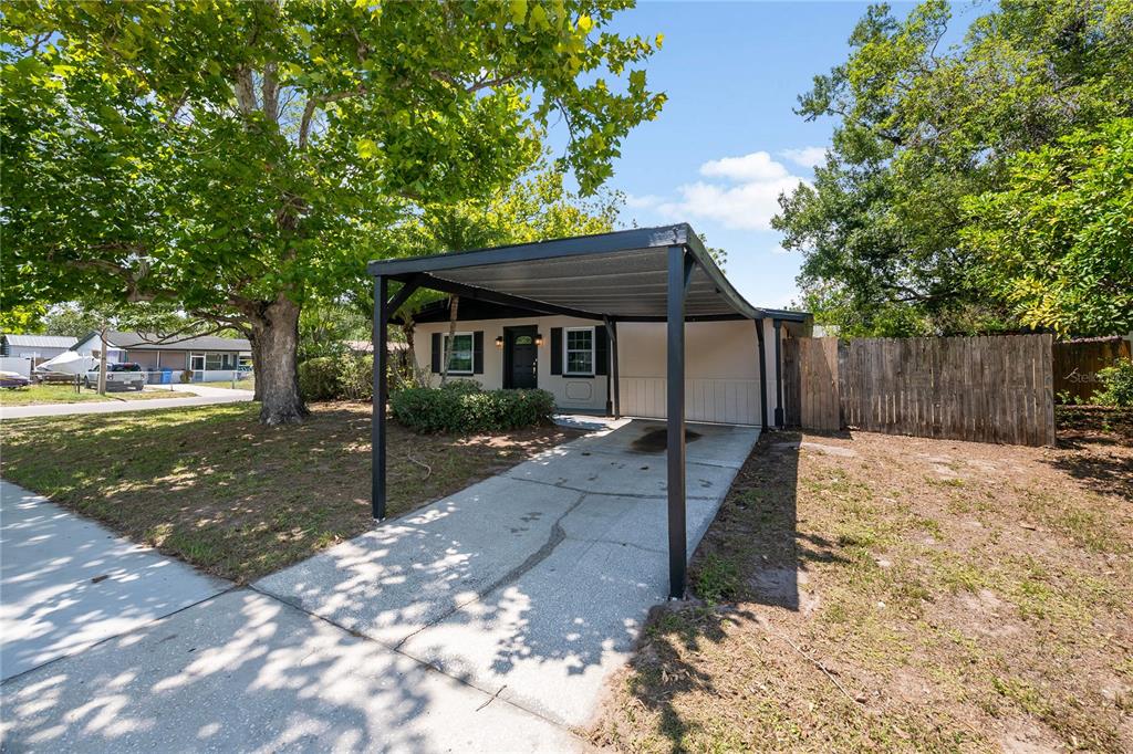 A single-story house with a black metal carport and a concrete driveway — 7402 WISHING WELL COURT, TAMPA, FL