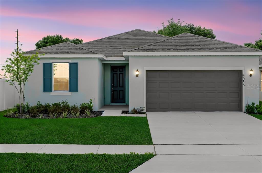 A single-story house with light blue stucco, a gray garage door, and a front lawn — 5055 ABIGAIL DRIVE, LAKE WALES, FL