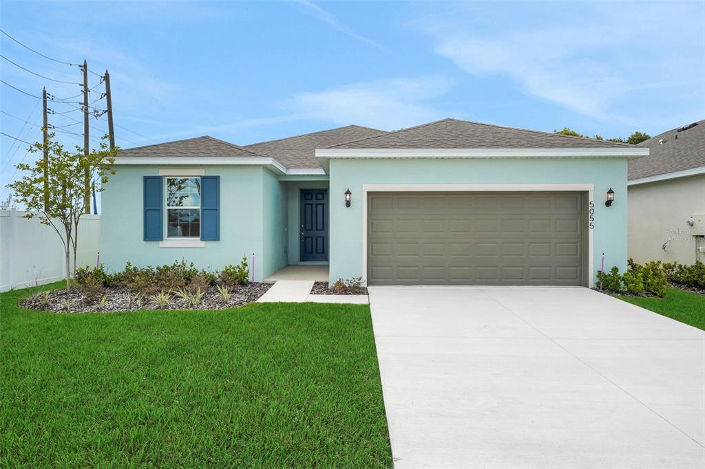 A light blue single-story house features a two-car garage, blue shutters, and a concrete driveway — 5055 ABIGAIL DRIVE, LAKE WALES, FL