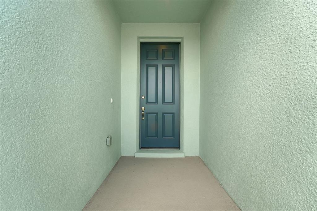 A dark blue front door is centered in a covered entryway with light green walls — 5055 ABIGAIL DRIVE, LAKE WALES, FL