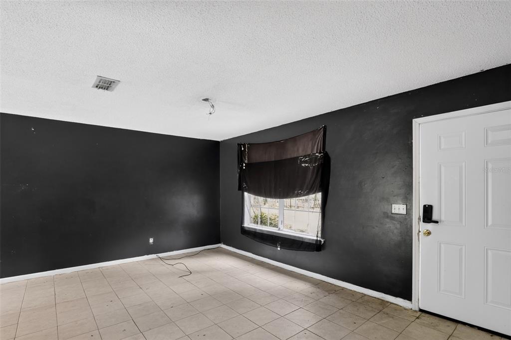 A room with black walls, tile flooring, a white door, and a window with curtains — 5179 MARCUS DRIVE, GREENWOOD, FL