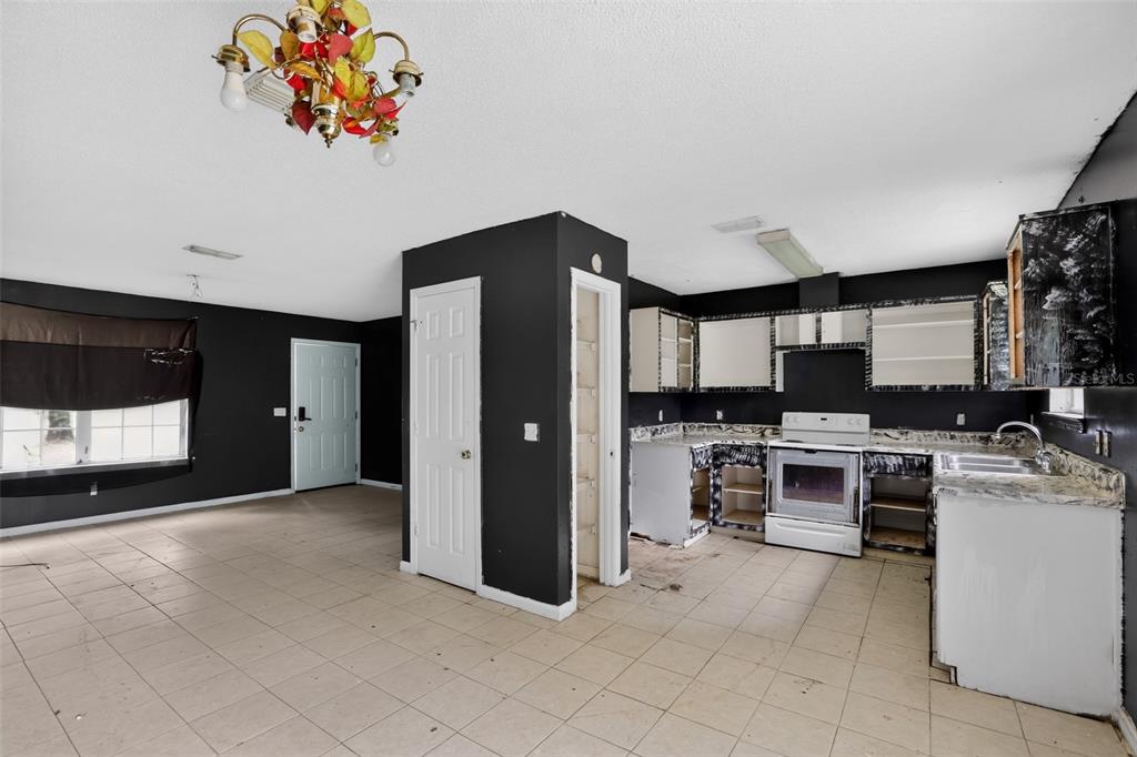 A kitchen and living area with black walls, white tile floors, and unfinished cabinetry — 5179 MARCUS DRIVE, GREENWOOD, FL