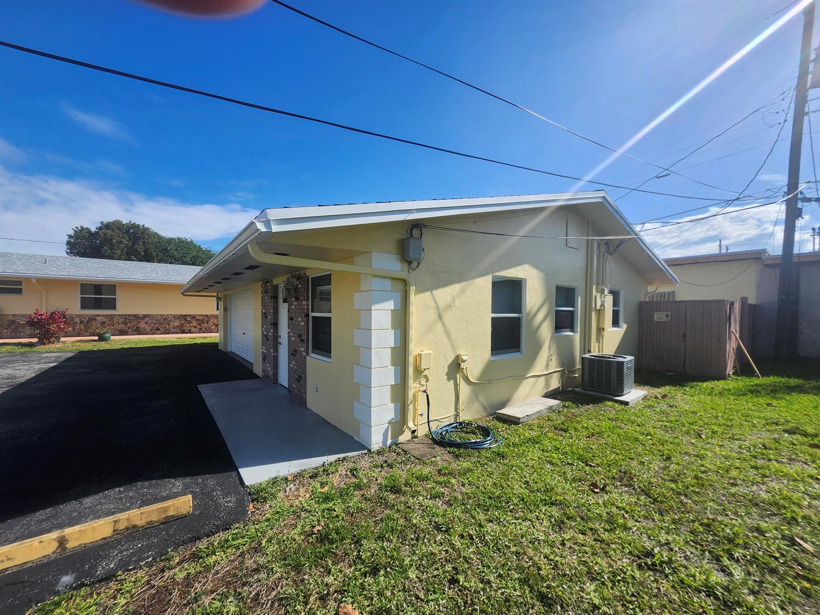 A yellow house exterior with a garage, brick accents, and a small concrete driveway — 511 N 60th Way, Hollywood FL 33024, HOLLYWOOD, FL