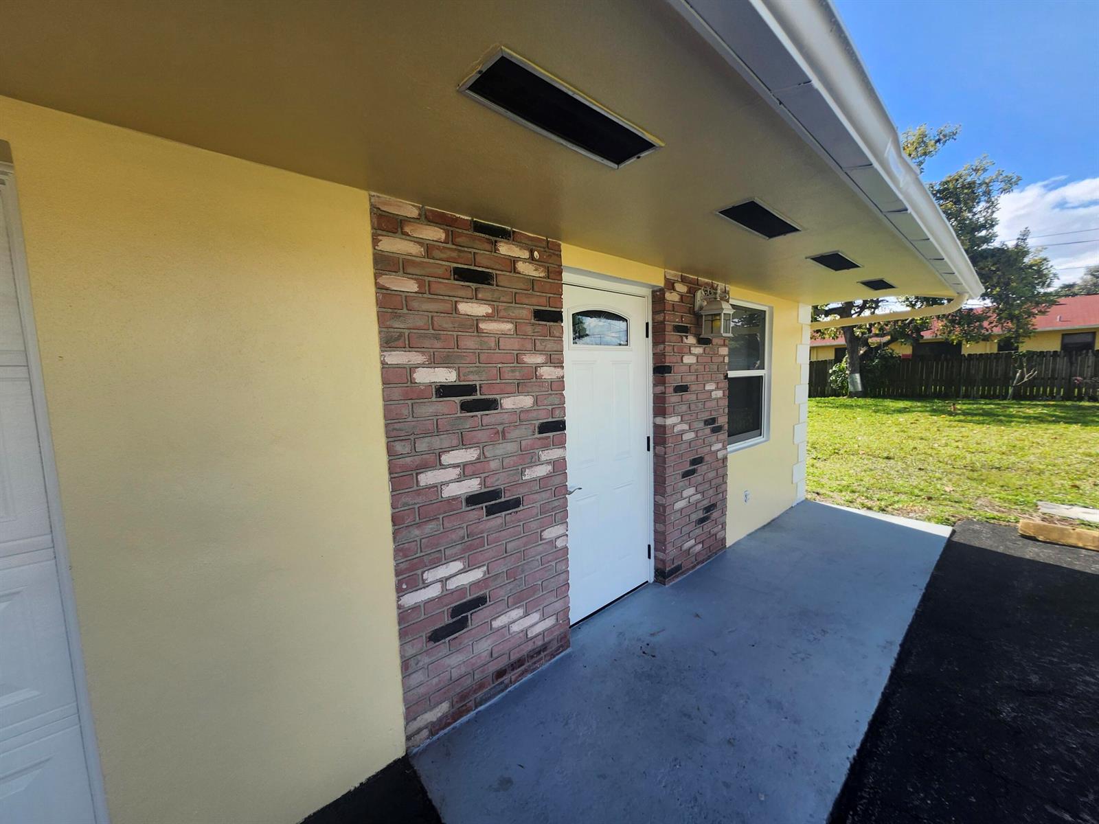 A yellow exterior wall features a brick accent section surrounding a white front door — 511 N 60th Way, Hollywood FL 33024, HOLLYWOOD, FL