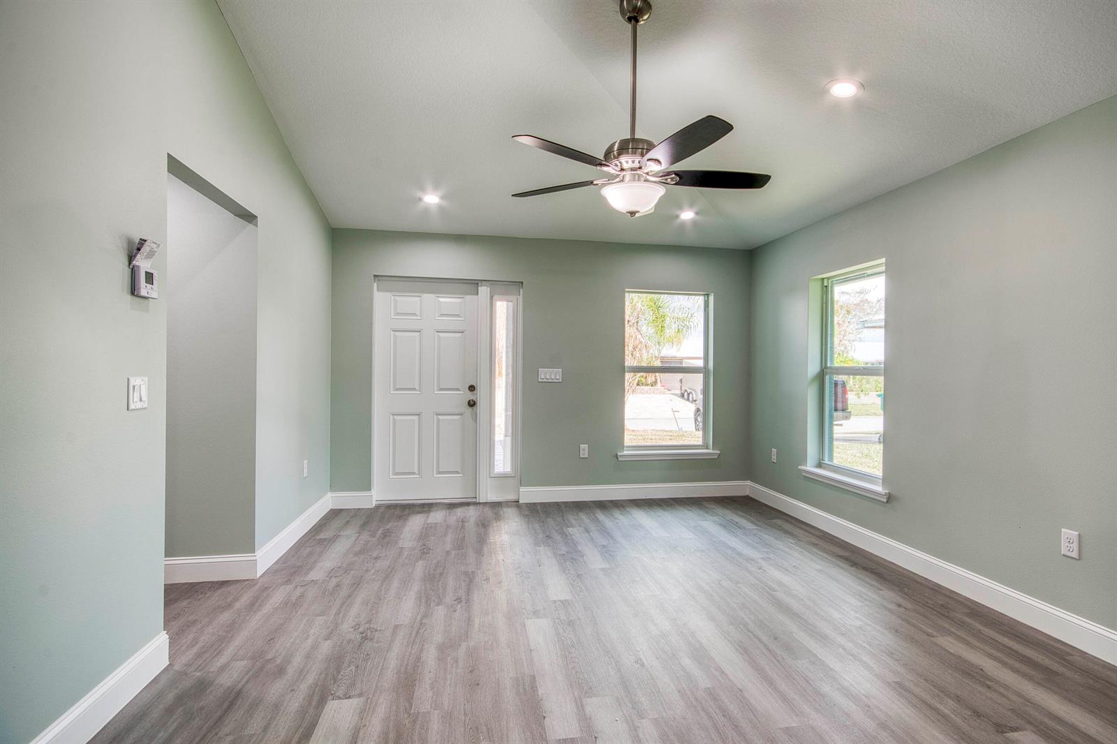A living room with light green walls, gray wood-look flooring, and a ceiling fan — 5108 SE 42nd Street, Okeechobee FL 34974, OKEECHOBEE, FL