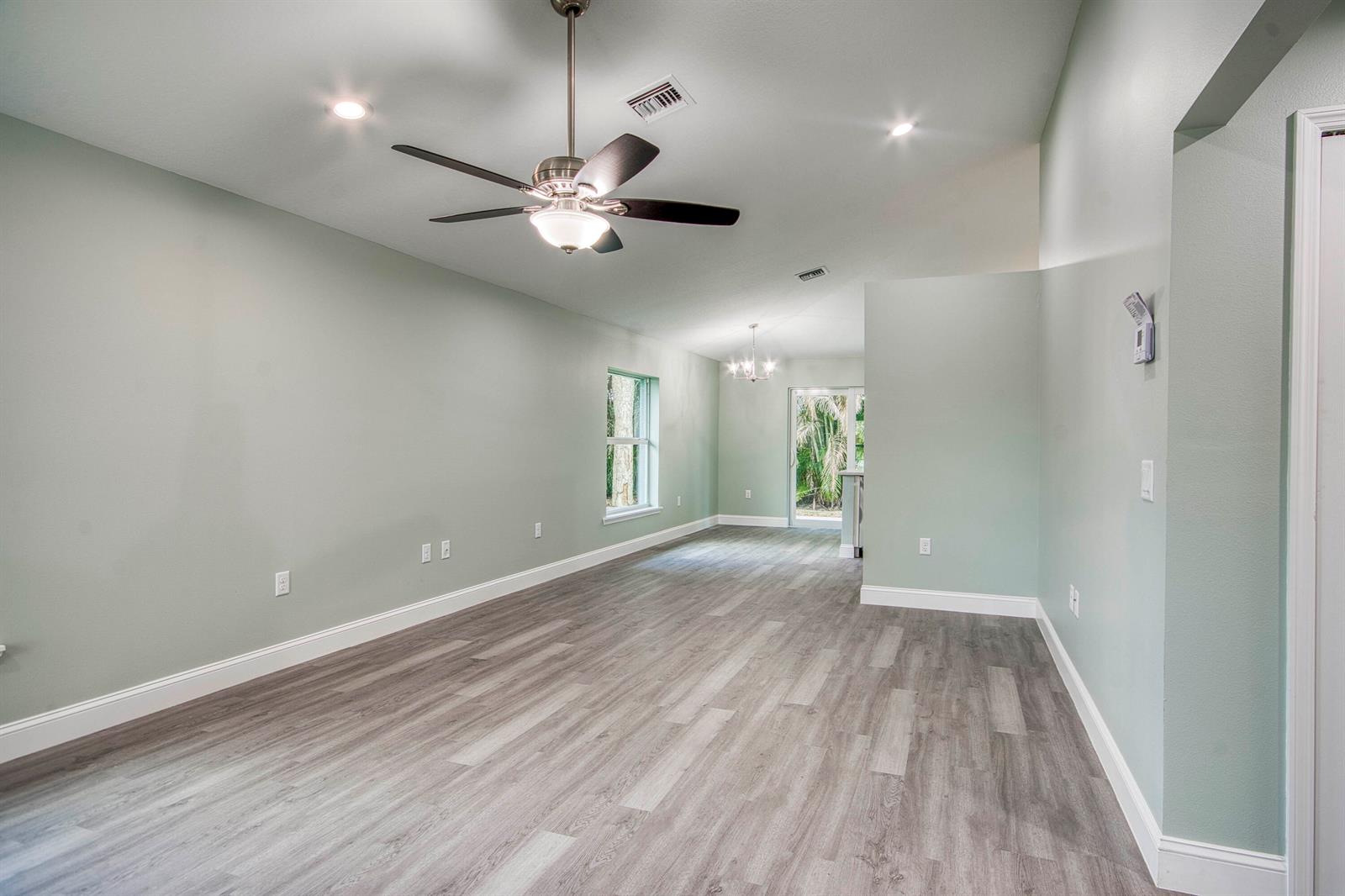An empty room with light green walls, gray wood-look flooring, and a ceiling fan — 5108 SE 42nd Street, Okeechobee FL 34974, OKEECHOBEE, FL