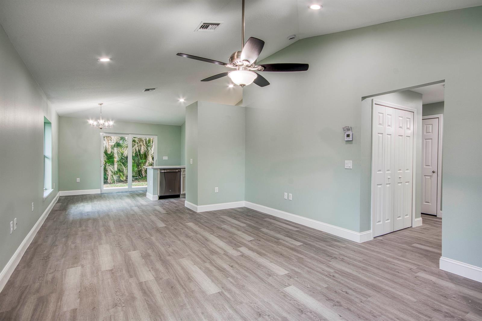 An open-concept living area features light green walls, wood-look flooring, a ceiling fan, and a kitchen — 5108 SE 42nd Street, Okeechobee FL 34974, OKEECHOBEE, FL
