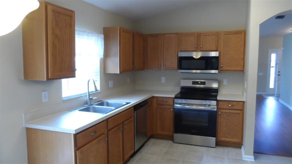 A kitchen features wood cabinets, stainless steel appliances, and white countertops — 30709 LANESBOROUGH CIRCLE, WESLEY CHAPEL, FL
