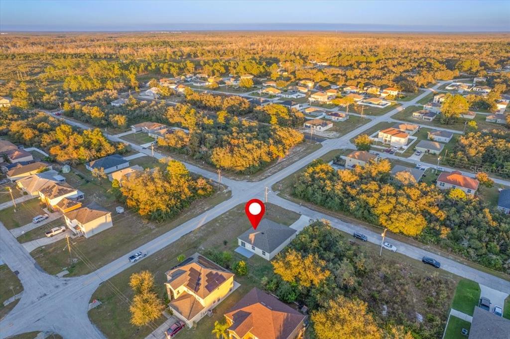 An aerial view shows a single-story house with a red map pin on its roof — 1200 WAHNETA DRIVE, KISSIMMEE, FL