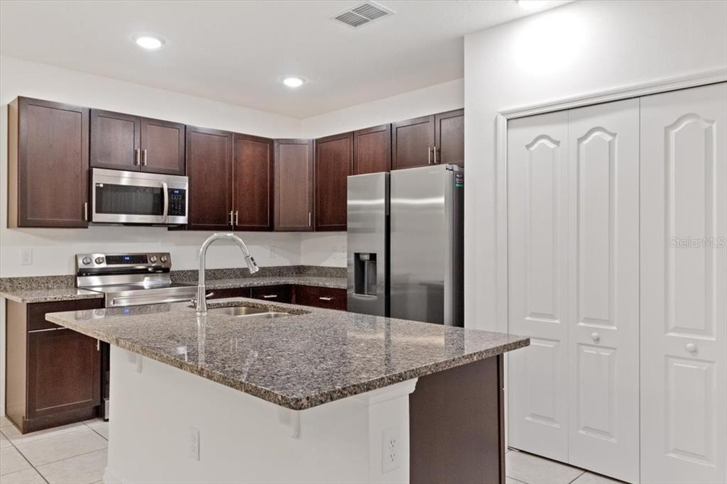 This open-concept living area features a kitchen with dark cabinets and a dining space — 1200 WAHNETA DRIVE, KISSIMMEE, FL