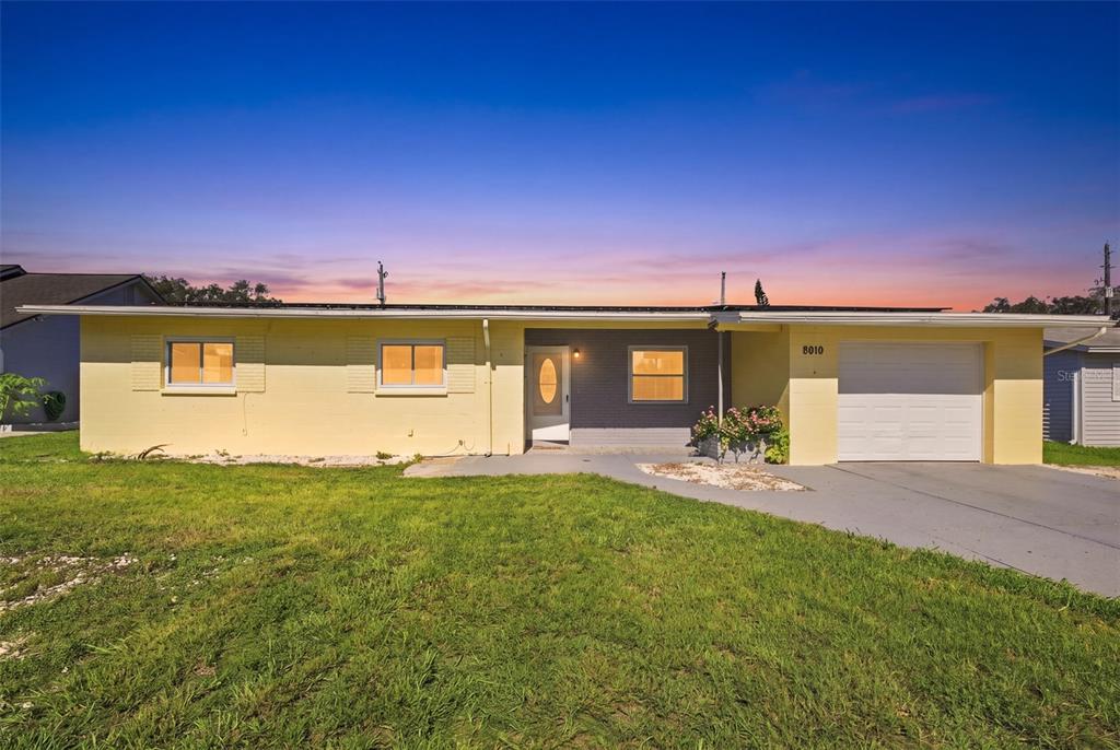 A single-story yellow house with a gray brick accent wall and an attached garage — 9810 N 54TH STREET, TEMPLE TERRACE, FL