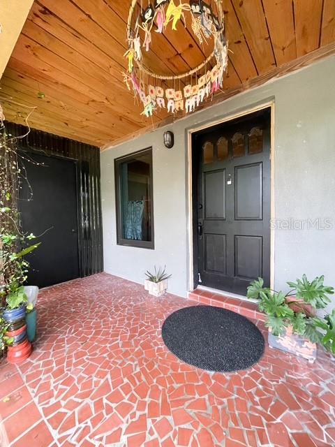 A covered porch features a red tile floor, a dark front door, and a hanging mobile — 306 CASLER AVENUE, CLEARWATER, FL