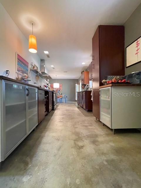 A kitchen features dark wood cabinetry, a concrete floor, and a hanging pendant light — 306 CASLER AVENUE, CLEARWATER, FL