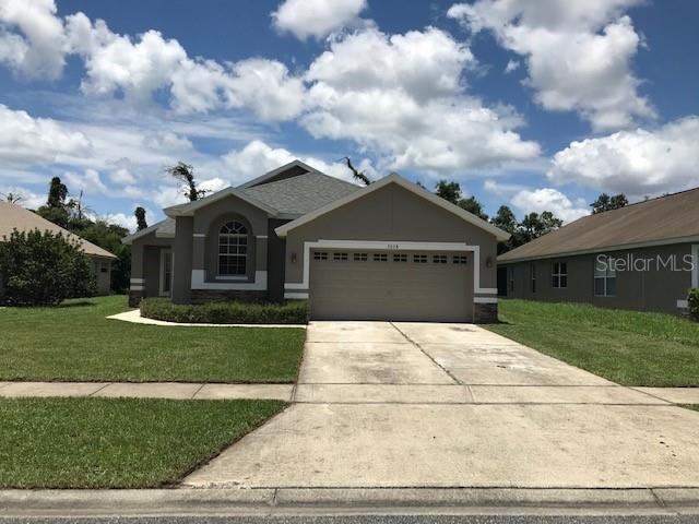 A single-story house with a two-car garage and a concrete driveway under a cloudy sky — 3078 VERBENA DRIVE, DELTONA, FL