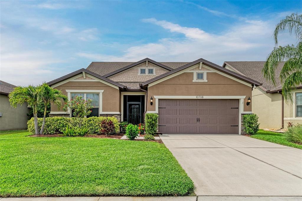 A single-story suburban house with a tan stucco exterior, a two-car garage, and a lawn — 10708 52ND COURT E, PARRISH, FL