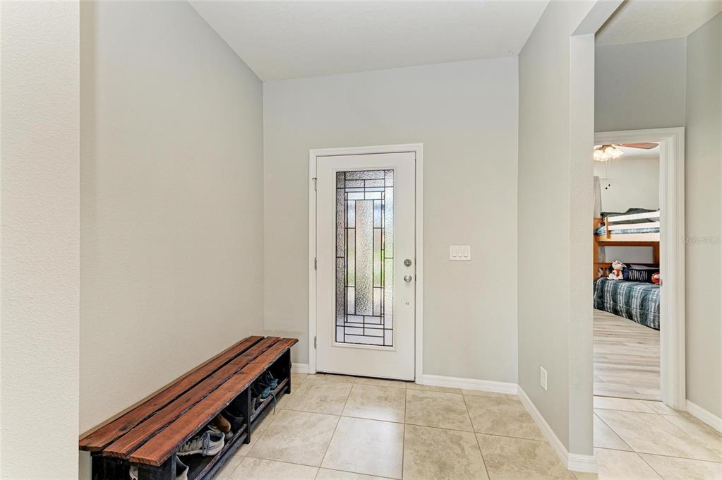 An entryway with a wooden shoe bench, tiled floor, and a front door with glass — 10708 52ND COURT E, PARRISH, FL