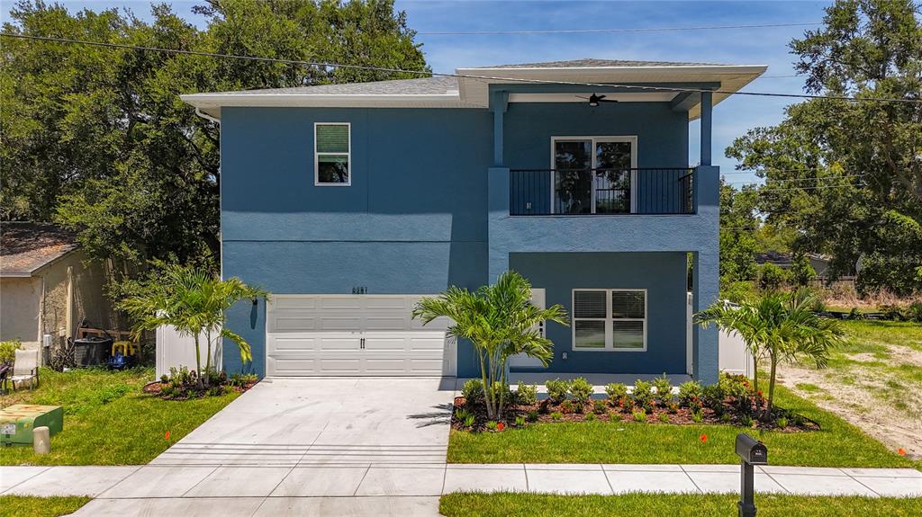 A two-story blue house with a garage, a balcony, and palm trees in the yard — 6481 28TH STREET N, ST PETERSBURG, FL