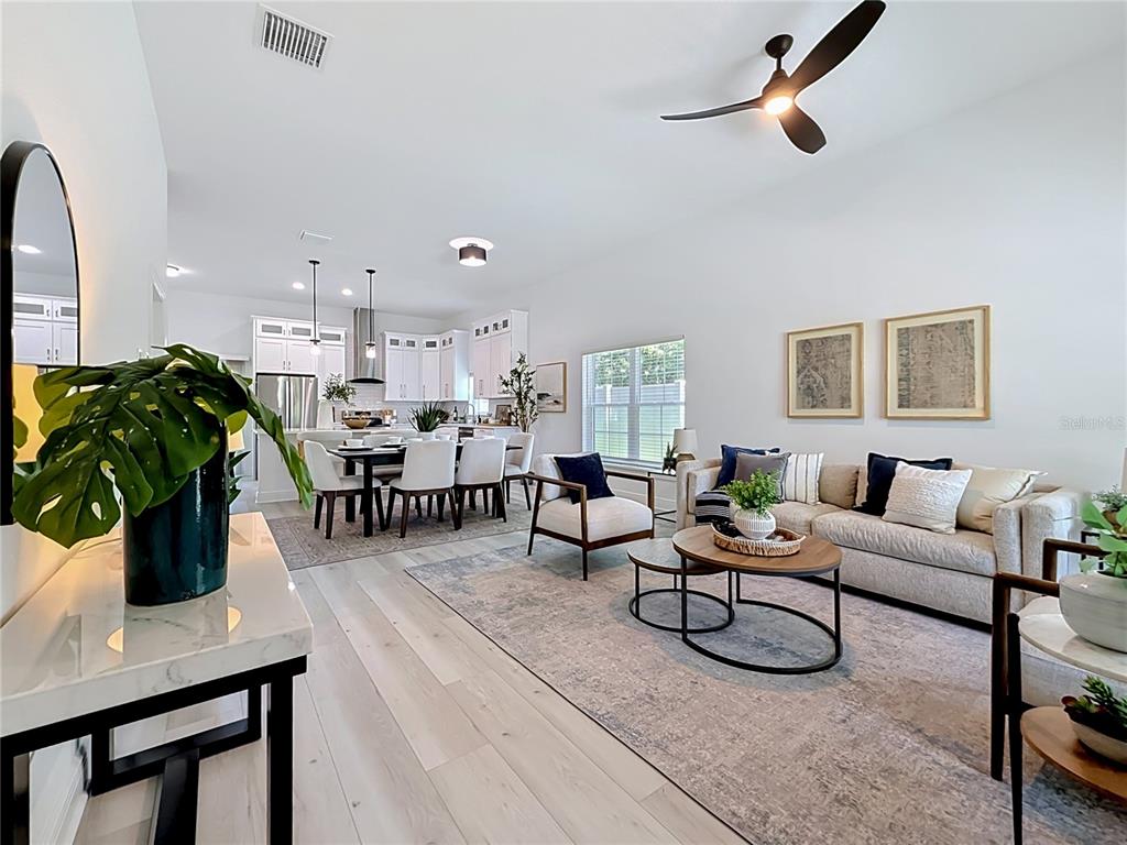 An open-concept living and dining area features light wood flooring, white cabinetry, and modern furniture — 6481 28TH STREET N, ST PETERSBURG, FL
