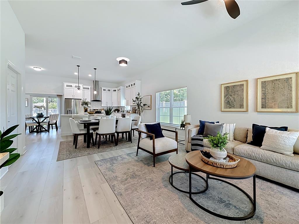 An open-concept living and dining area features white cabinetry, light wood flooring, and neutral furniture — 6481 28TH STREET N, ST PETERSBURG, FL