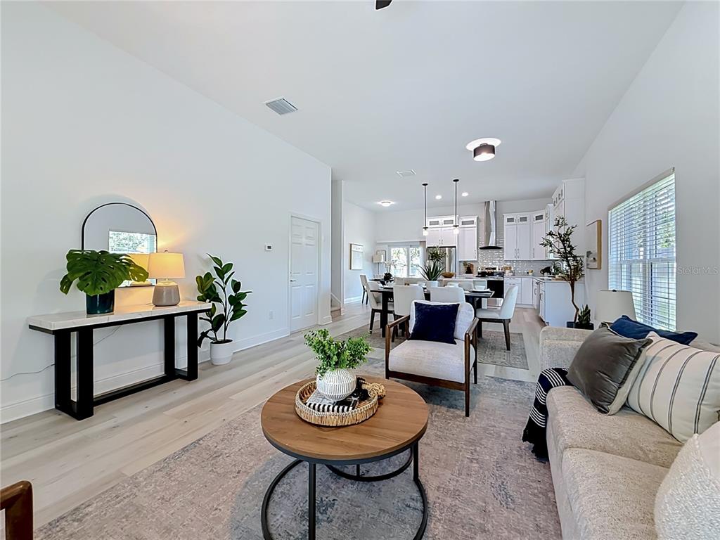 An open-concept living and dining area features light wood flooring, white walls, and modern furniture — 6481 28TH STREET N, ST PETERSBURG, FL