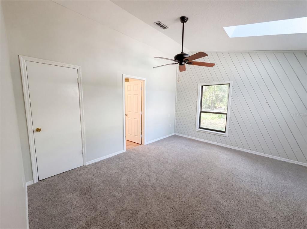 A bedroom with gray carpet, a vaulted ceiling, a ceiling fan, and diagonal wood paneling — 3739 LAKE GRIFFIN ROAD, LADY LAKE, FL