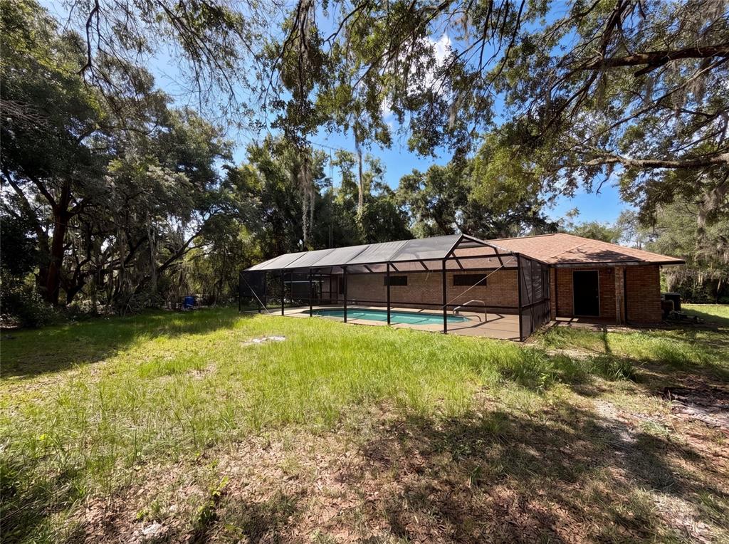 A brick house with a screened-in pool sits in a grassy, tree-shaded backyard — 3739 LAKE GRIFFIN ROAD, LADY LAKE, FL