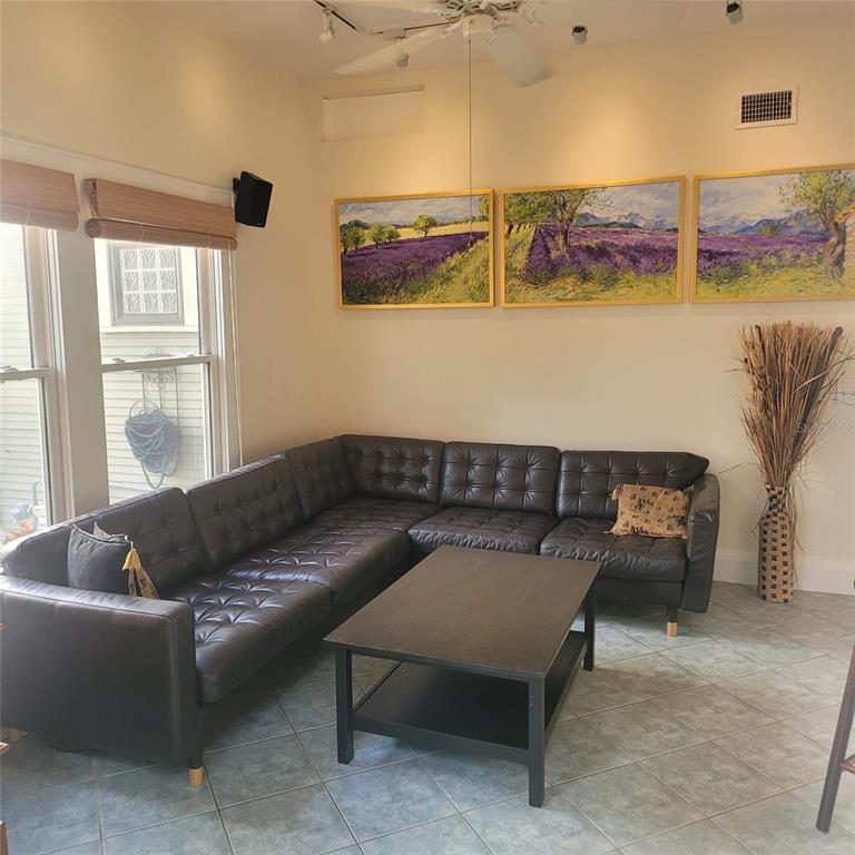 A living room features a large black leather sectional sofa, a coffee table, and wall art — 2916 W BAY COURT AVENUE, TAMPA, FL