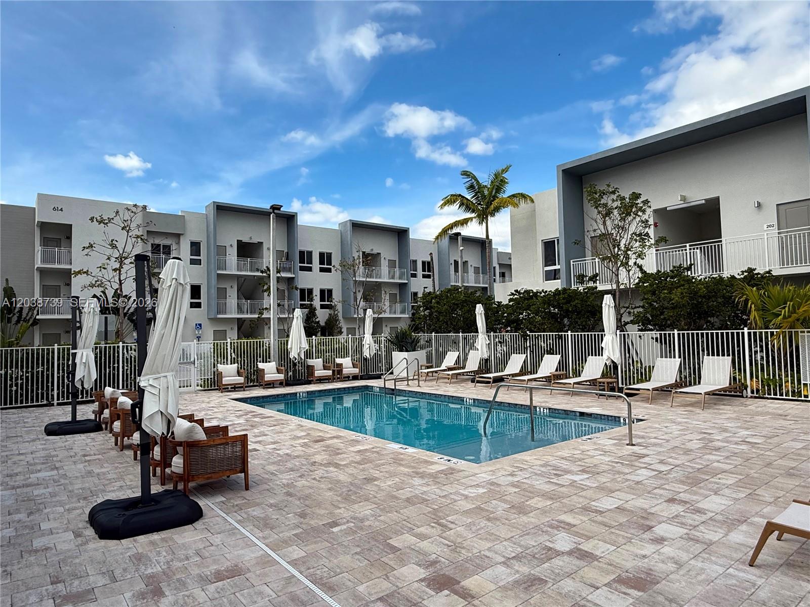 A rectangular swimming pool is surrounded by lounge chairs and umbrellas on a paved deck — 610 NE 2nd St # 301, Dania Beach FL 33004, DANIA BEACH, FL