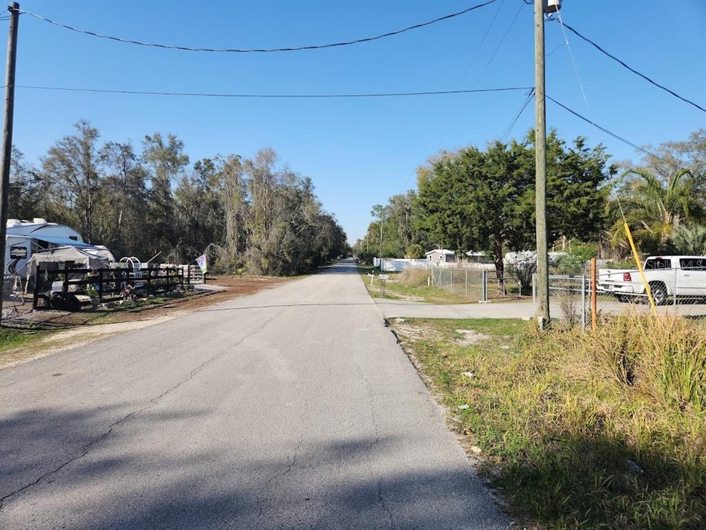 A paved road stretches into the distance between wooded areas, a parked RV, and a truck — LOT 19 NW 119 TH COURT, OCALA, FL