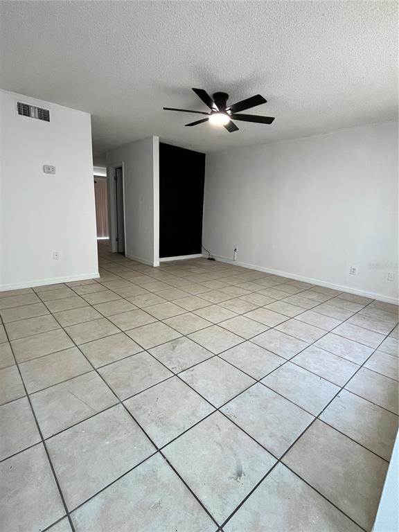 An empty room features light-colored tile flooring, white walls, and a ceiling fan — 4023 HENLEY ROAD UNIT 1702, ORLANDO, FL