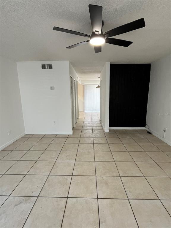 A room with light-colored floor tiles, a ceiling fan, and a black accent wall — 4023 HENLEY ROAD UNIT 1702, ORLANDO, FL