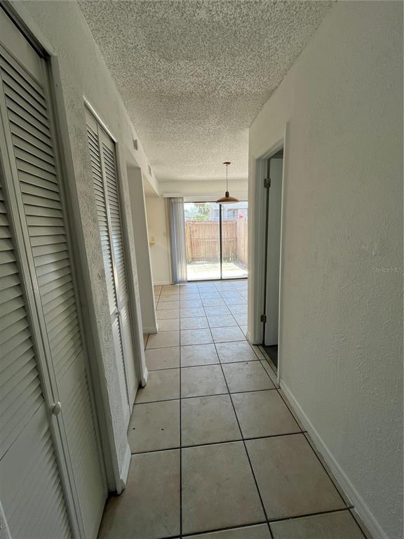 A tiled hallway leads to a living area with a sliding glass door to a patio — 4023 HENLEY ROAD UNIT 1702, ORLANDO, FL