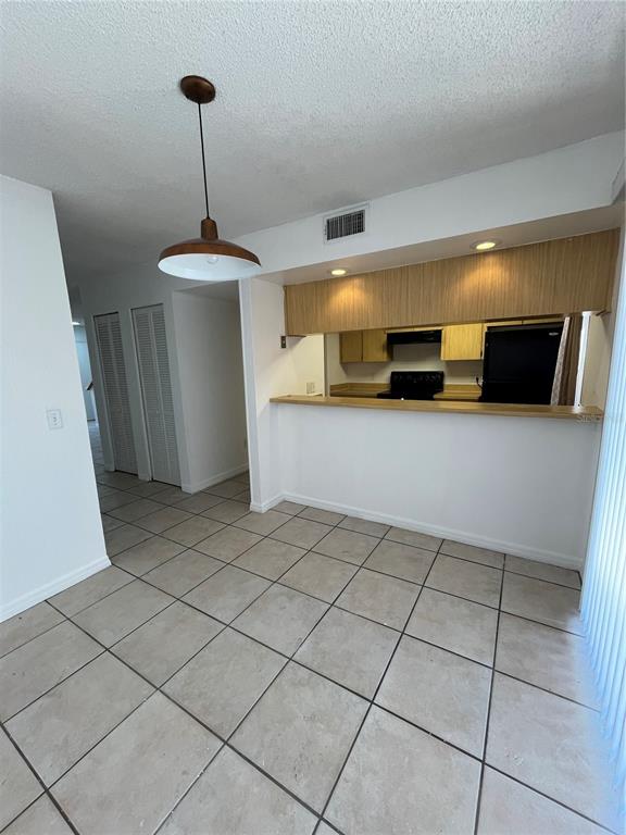 A kitchen with a breakfast bar, tile flooring, and a pendant light in the dining area — 4023 HENLEY ROAD UNIT 1702, ORLANDO, FL
