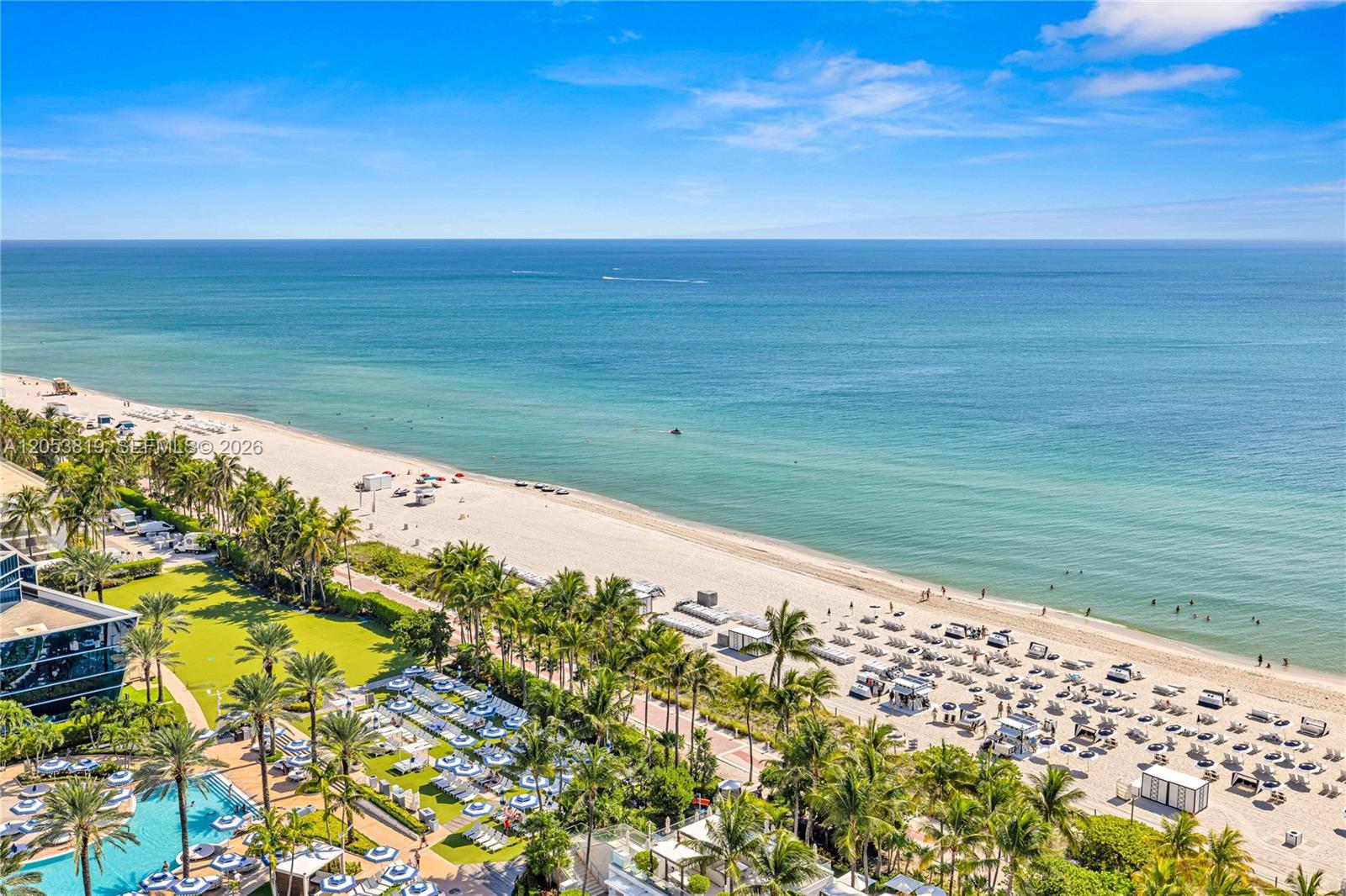 An aerial view shows a sandy beach with palm trees, lounge chairs, and the ocean — 4391 COLLINS AVE # 1706, Miami Beach FL 33140, MIAMI BEACH, FL