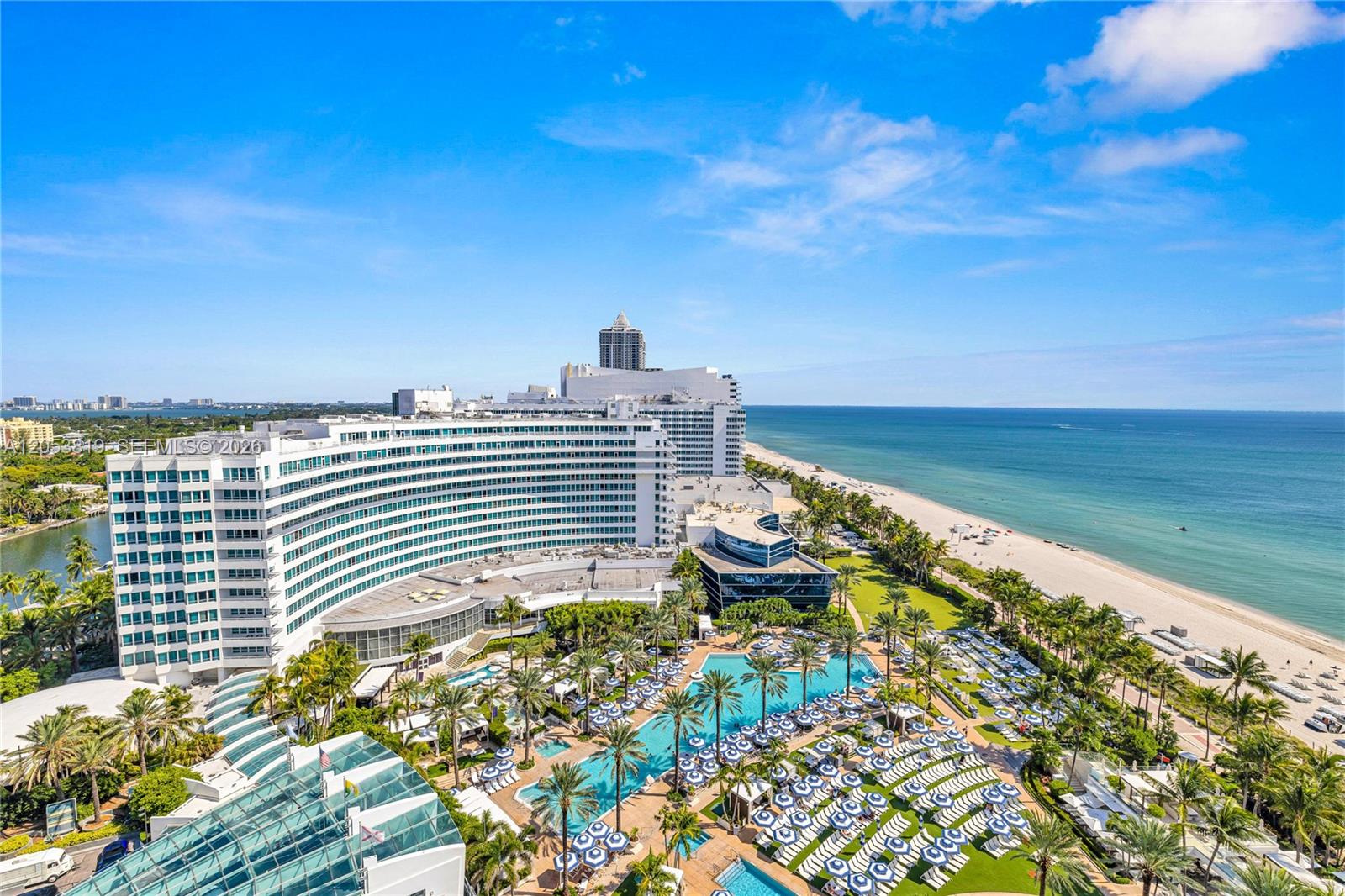 An aerial view shows a large curved hotel resort complex situated along a sandy beach — 4391 COLLINS AVE # 1706, Miami Beach FL 33140, MIAMI BEACH, FL