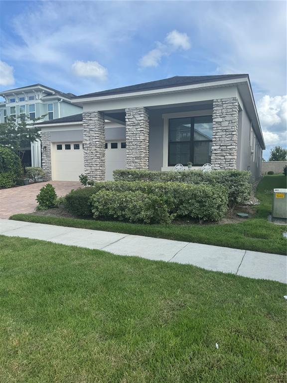 A single-story house features a stone-columned porch, a two-car garage, and a landscaped front yard — 2514 NOUVEAU WAY, KISSIMMEE, FL