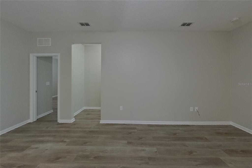 An empty room with light gray walls, wood-look flooring, and two doorways — 15724 PINE SISKIN LOOP, MASCOTTE, FL